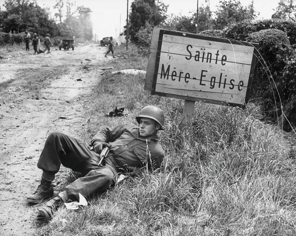 Lepäämässä oleva yhdysvaltalainen laskuvarjohyppääjä Sainte-Mère-Église'n lähellä | Taidetuloste historiallisesta valokuvasta